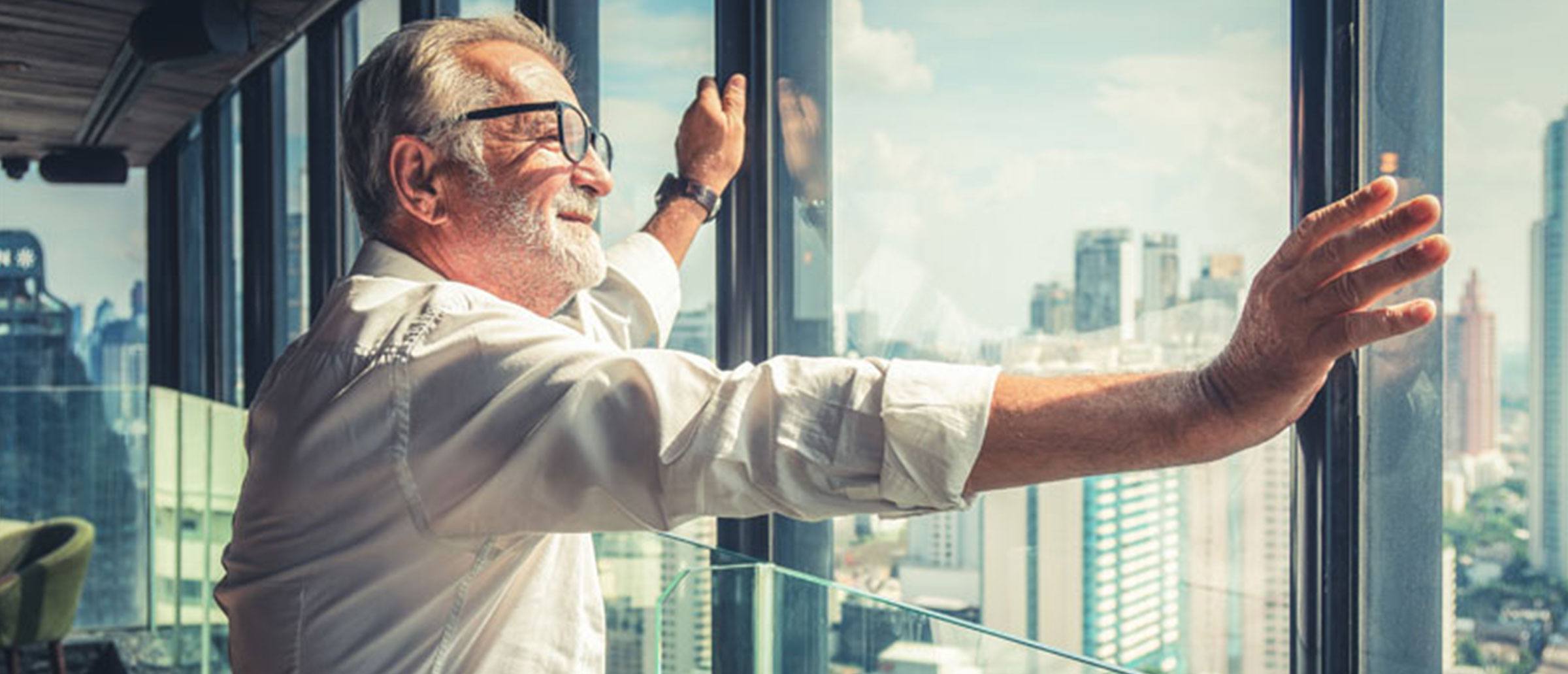 An older businessman gazing out of a window, taking in the city skyline