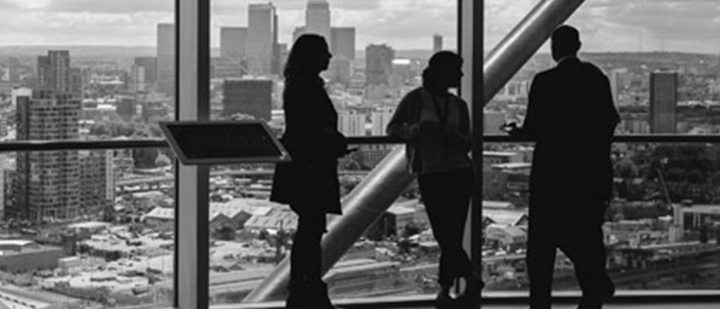 Silhouette business professionals conversing in front of a big glass window overlooking a city